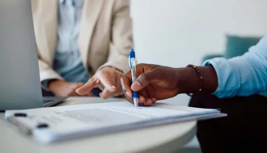 Person sitting at a table and signing an insurance document