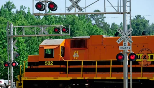 Railroad crossing on a street with a train traveling across it
