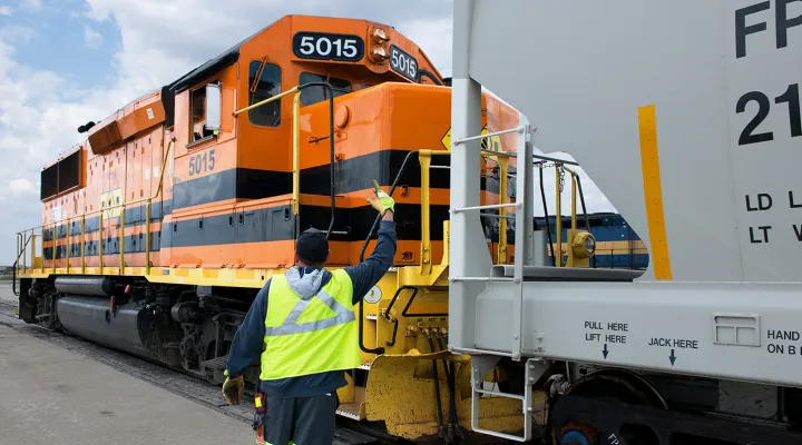 G&W employee wearing a high-visibility vest directing the front of a train